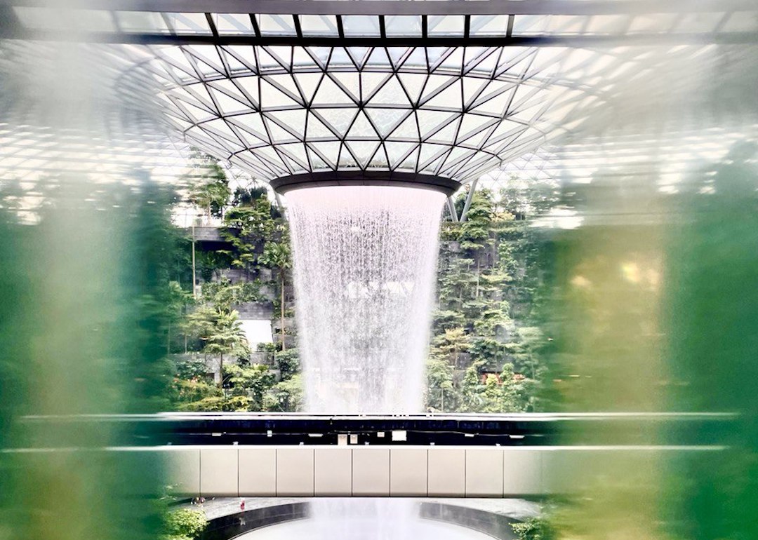 taking instagram photos of jewel changi waterfall in singapore with reflective and pinhole effects through architectural features of jewel changi airport