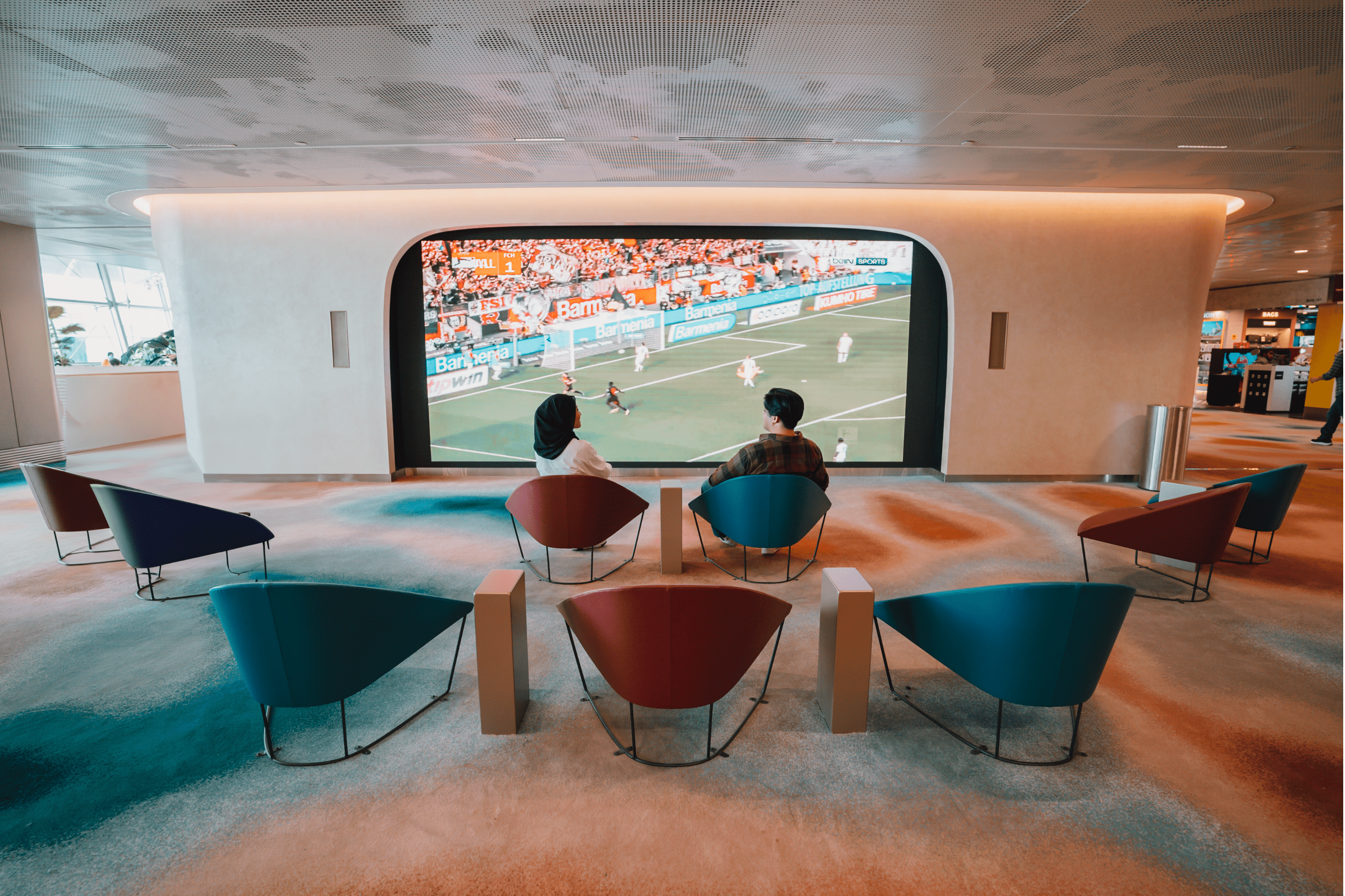 Travellers watching a football match at Terminal 2 TV Lounge