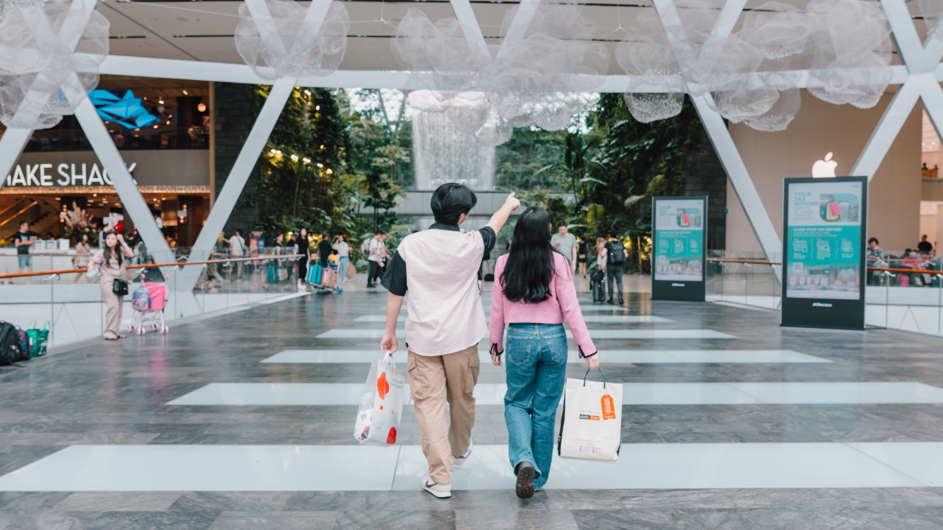 two friends entering jewel changi airport with shopping bags