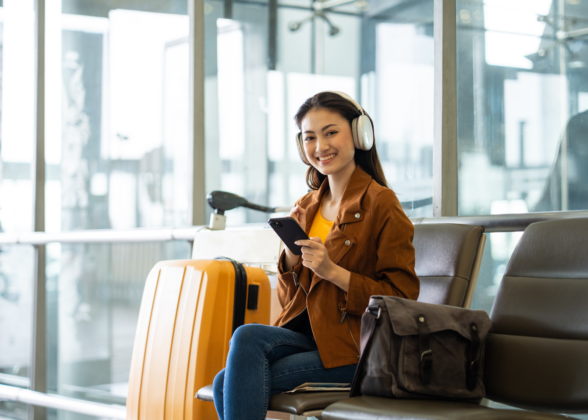 Woman travelling holding phone with luggage smiling 