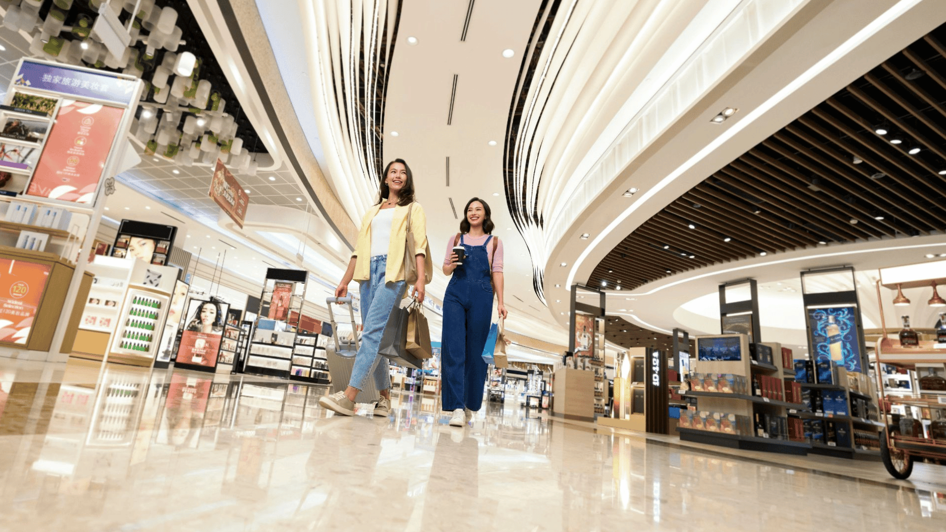 Two women smiling and holding shopping bags and enjoying duty-free shopping in the bright, modern transit area of Changi Airport. 